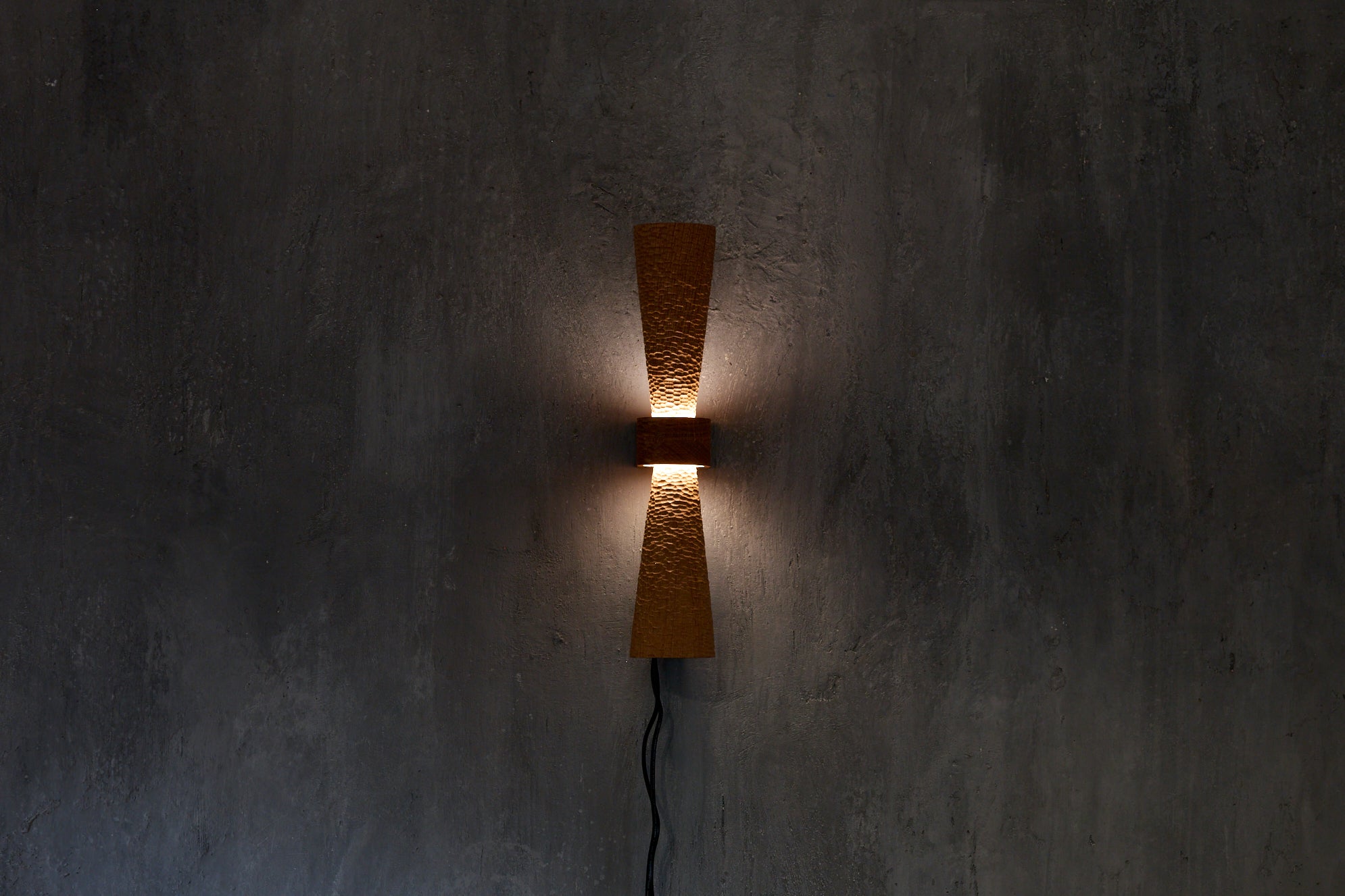 Sconce with a tiny scallop-textured and tapered upper and lower standoff allowing the texture to graduate from full light at the centre to diminished light at the ends really allowing the texture to come alive. It is just as beautiful in an entirely different way when not lit giving the sconce a whole new complexion.