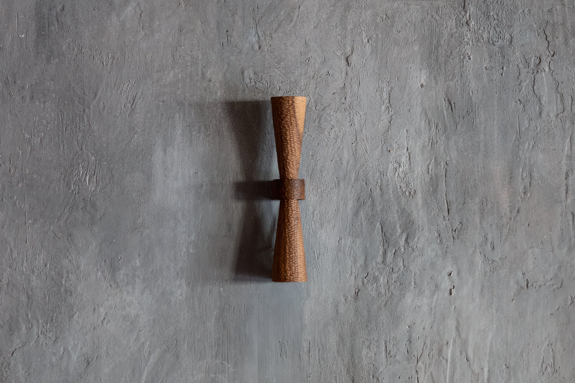 Sconce with a tiny scallop-textured and tapered upper and lower standoff allowing the texture to graduate from full light at the centre to diminished light at the ends really allowing the texture to come alive. It is just as beautiful in an entirely different way when not lit giving the sconce a whole new complexion.